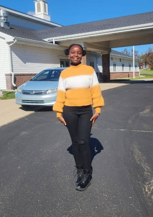 Emily Mwangi wearing a Yellow Sweater and Black Pants